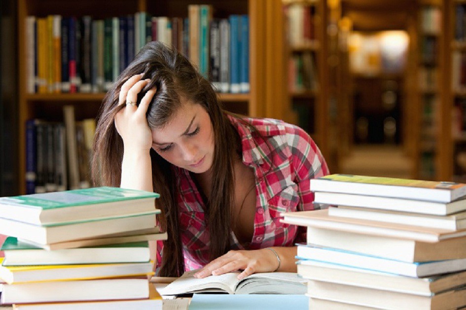 transferencia-de-faculdade - jovem com semblante de preocupação em frente aos livros